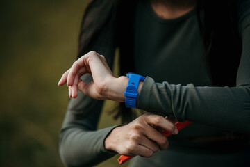 Unrecognizable woman checking her smartwatch during an outdoor jog. Sport and lifestyle tech concept