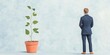 © GraphzTain - A businessman stands thoughtfully next to a growing plant, symbolizing growth, potential, and new beginnings in a serene setting.