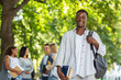 © Prostock-studio - Happy black student with books smiling at camera, spending time with his friends in public park, copy space