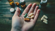 © SMPTY - Hand holding assorted pills and supplements, health and medication concept on wooden surface