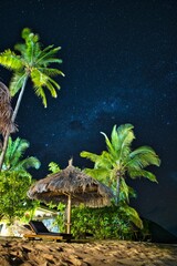 Wall Mural - portrait image of stars and the milky way above a lounge chair and an umbrella on the beach. amazing
