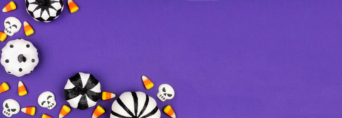 Sticker - Halloween corner border of black and white pumpkin decor and candy. Above view on a purple banner background with copy space.