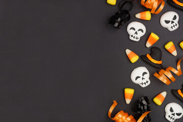 Wall Mural - Halloween side border of black, white and orange color candy and ribbon. Overhead view on a black background with copy space.