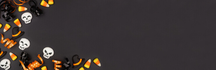 Poster - Halloween corner border of black, white and orange color candy and ribbon. Above view on a black banner background with copy space.