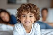 © Anupam - Happy son. Portrait of cheerful little latin boy smiling at camera, playing with his parents and siblings on a bed at home, Generative AI