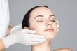 © Elena - woman with a beautiful face and smooth skin is having a facial cosmetic check-up by a professional doctor in white gloves, for clinic and cosmetology service, beauty concept poster, banner