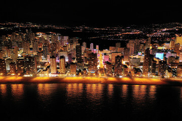 Wall Mural - Skyline of Spanish city Benidorm, at night. Street lights. Light reflection in water. Spectacular travel destination in south of Spain, Alicante province.  