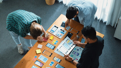 Top view of smart Ui designer brainstorming and planning about Ux Uo design or mobile interface wireframe design with diverse develop team. Caucasian programer walking and joining meeting.Convocation.