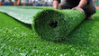 © JVLMediaUHD - Worker installing a roll of artificial grass on a sports field in the afternoon