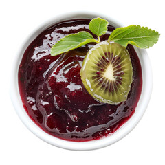 Wall Mural - A close-up overhead view of a white bowl filled with red berry jam, garnished with a slice of kiwi and a sprig of mint.