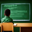 © GenBy - Young student sitting alone at desk, facing a chalkboard in a classroom. Back to school concept with focus on education and learning.