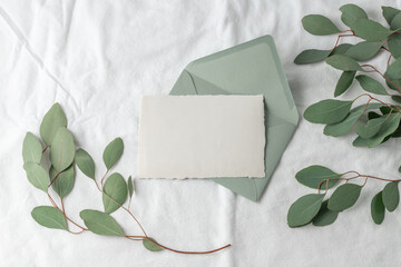 Blank retro paper card  with blue green envelope and aroma eucalyptus twigs on white linen background.