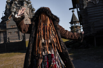 Shamanic dances, a shaman woman in a folk costume with lots of fringes and ribbons, dancing and spinning with her hands raised , in a village among wooden architecture, Slavic or Nordic style