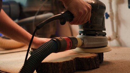 Sticker - Craftsperson works with orbital sander on lumber block to achieve smooth finish, close up shot. Woodworking specialist in furniture assembly shop using angle grinder to fix wooden surface, camera A