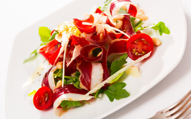 Wall Mural - Colorful salad from duck ham with fresh arugula, tomatoes, sliced parmesan cheese, pine nuts and orange