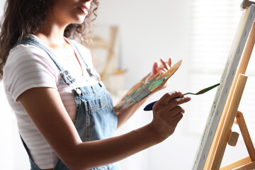 Wall Mural - Woman drawing picture with palette knife in studio, closeup