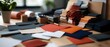 © Supranee - A vibrant collection of colored paper swatches arranged on a stylish workspace, perfect for creative projects and design inspiration.