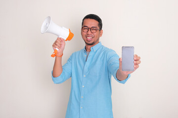 Wall Mural - A man smiling happy and holding megaphone while showing blank phone screen display