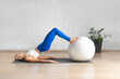 © junky_jess - Workout with fitness ball. Fit Caucasian woman practice hamstring roll-in using props in loft studio indoor.