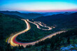 © guoquan - At night, on the winding mountain road, the car lights form a long stream of light