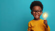 © Natalia Klenova - Smart boy with glasses holding a light bulb on blue background