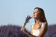 © Antonioguillem - Woman smelling lavender flowers in a sunny field