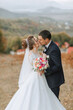 © Vasil - A bride and groom kiss in a field. The bride is wearing a white dress and the groom is wearing a suit