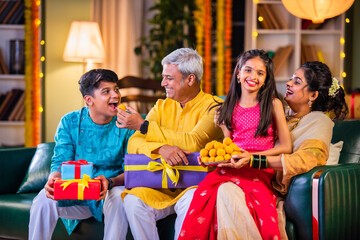 Indian family enjoying Diwali festival night with sweets and gifts in traditional attire at home