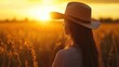 © Theeranan - A peaceful scene of a woman in a cowboy hat in a field, with the warm colors of sunset casting a golden glow.
