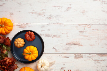 Wall Mural - Rustic home desk table with blue plate with pumpkins and flowers. Top view, flat lay, copy space. Autumn composition.