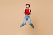 © ViDi Studio - Full body young shocked surprised happy woman she wear red t-shirt casual clothes jump high spread hands look camera isolated on plain pastel light beige background studio portrait. Lifestyle concept.