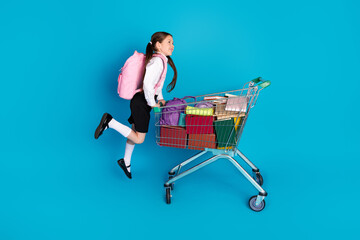 Canvas Print - Full body portrait of little schoolchild uniform jump market trolley isolated on blue color background