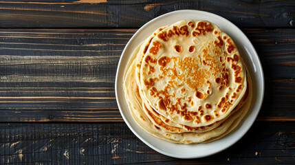 Poster - Wheat tortillas stacked on a white plate, placed on a rustic wooden tabletop