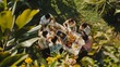© VK Studio - An aerial view of a joyous outdoor gathering where six friends enjoy a meal around a garden table adorned with fruits and drinks, surrounded by lush greenery.