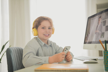 Poster - Photo of charming cute girl schoolkid sitting chair table desk studying from home modern technology daylight indoors