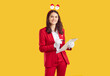 © Studio Romantic - Smiling woman wearing in Santa style with horns in the shape of santa's heads making notes in notepads on yellow background and looking at camera. New Year's Christmas survey of customers in the mall.