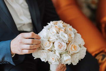 Wall Mural - A man is holding a bouquet of white roses in his hand