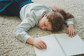 Poster - Photo of sweet pretty cute adorable girl learner lying fluffy carpet doing homework cozy home room interior indoors