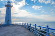 © Akarat - A small white lighthouse stands at the end of a breakwater