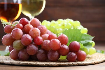 Fresh ripe grapes and glasses of wine on wooden table, closeup