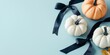 © netrun78 - A beautiful flatlay features white and orange pumpkins adorned with dark ribbons, creatively arranged on a soft blue surface.
