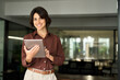 © insta_photos - Happy professional female company executive, smiling Hispanic business woman entrepreneur, businesswoman corporate leader manager standing in office looking at camera using tablet. Portrait.