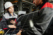 © Clique Images - Workers examining solar panel in industrial setting wearing protective gear