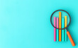 © tonstock - Colorful bar graph and magnifying glass on a bright blue background, representing data analysis, business statistics, and market research.