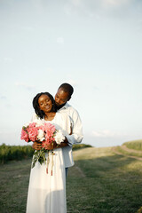 Happy romantic couple hugging in a summer field