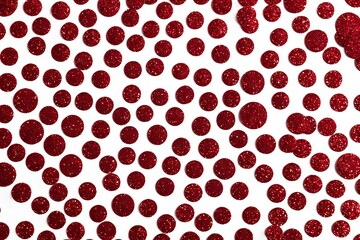 Red glitter confetti scattered on a white background. Close up. Festive and celebratory abstract pattern for holiday design and decoration projects