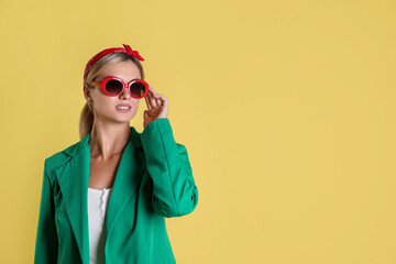 Poster - Beautiful woman in stylish green jacket on yellow background, space for text