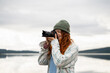© ADDICTIVE STOCK - Woman taking photos at lake during camping trip