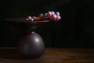 Red grapes in a brown etagere against a black background with copy space, dark and moody still life with fruits, copy space, selected focus