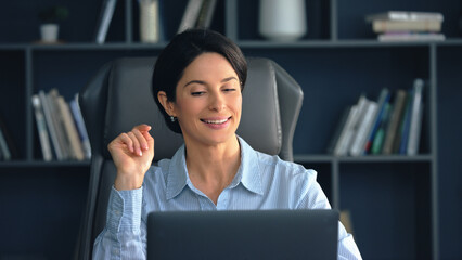 Happy businesswoman working on laptop in modern